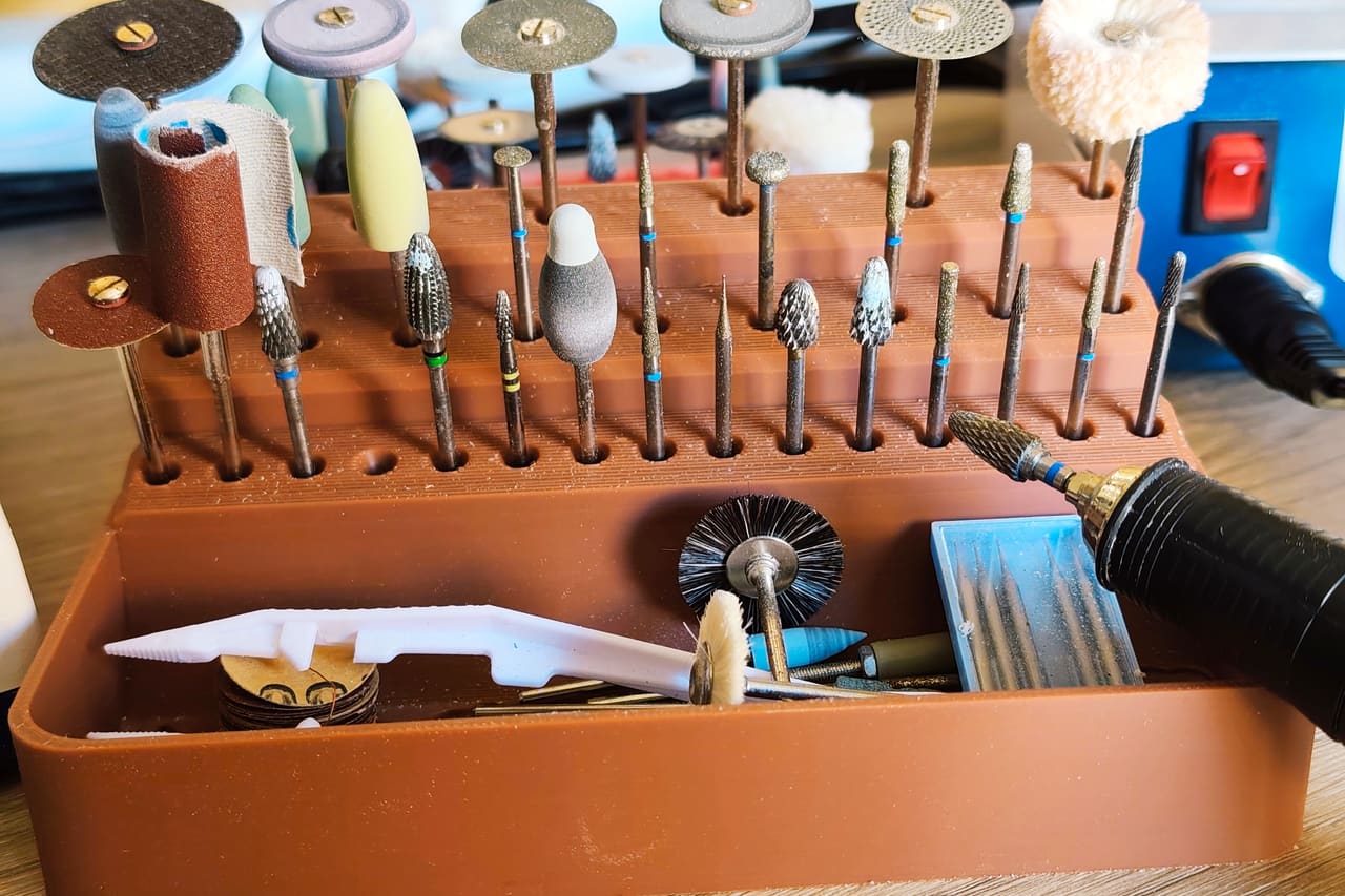 Fraises, disques de polissage et brosses rangés dans un support, outils du laboratoire